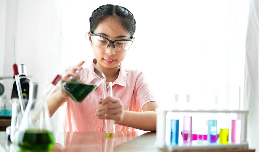 Girl wearing safety goggles and conducting chemistry experiment