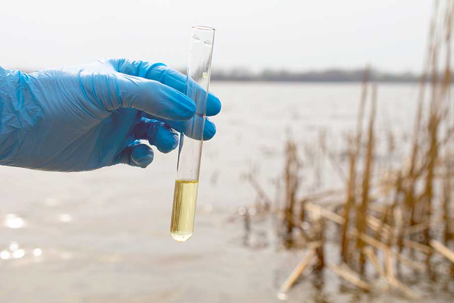 chemist taking water sample for testing from lake